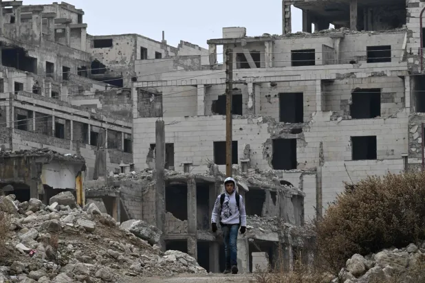 صبي يمشي بين أنقاض المباني في حي الخالدية في حمص (أ.ف.ب)