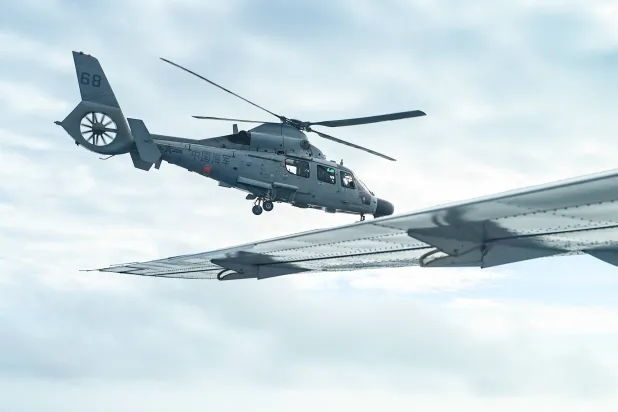 مروحية تابعة للبحرية الصينية (يسار) تحلق بالقرب من طائرة مكتب مصايد الأسماك والموارد المائية (BFAR) خلال رحلة استطلاعية جوية في سكاربورو شول في بحر الصين الجنوبي (أ.ب)