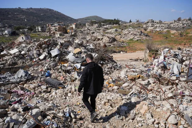 رجل يسير بين ركام المنازل في كفركلا (رويترز)
