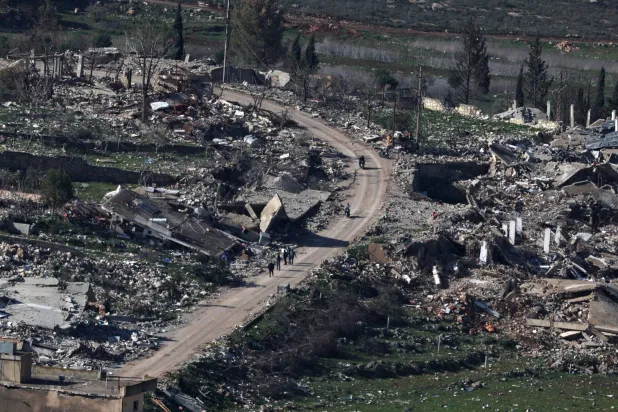 لبنانيون يسيرون على طول طريق على الجانب اللبناني من الحدود مع إسرائيل وسط الدمار في قرية ميس الجبل بجنوب لبنان في 18 فبراير 2025 (إ.ب.أ)
