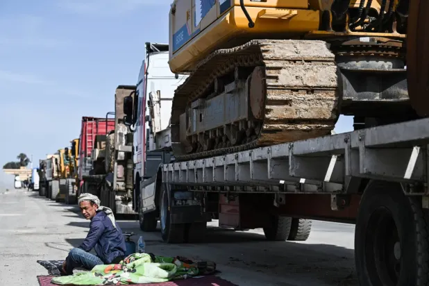 Bir sürücü, Refah sınır kapısını geçmeyi beklerken Gazze'ye giden yeniden inşa ekipmanı yüklü kamyonunun yanında
