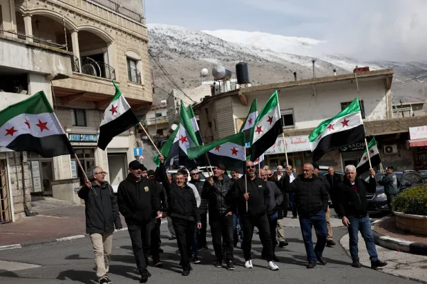 سوريون دروز من مجدل شمس المحتلة يرفعون الأعلام السورية ويحيون الذكرى الثالثة والأربعين لإضرابهم العام ضد قرار الضم الإسرائيلي للجولان الجمعة الماضي (إ.ب.أ)