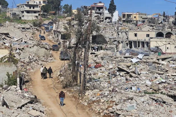 Lebanese walk through rubble in destroyed Meis El-Jabal, Lebanon (Asharq Al-Awsat)