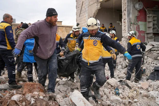 عناصر من الدفاع المدني السوري يحملون جثة أحد القتلى بعد انفجار مخلفات حرب في بلدة النيرب بريف إدلب الشرقي يوم 20 فبراير 2025 (إ.ب.أ)