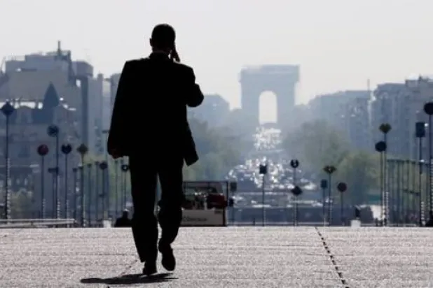 رجل أعمال يسير على رصيف «لا ديفانس» في الحي المالي والتجاري غرب باريس (رويترز)