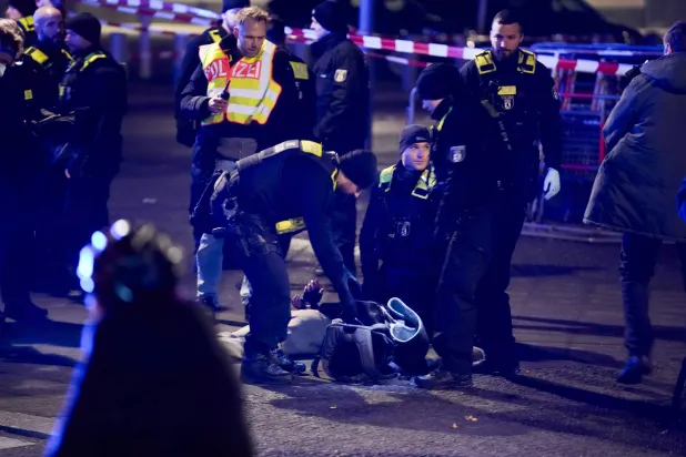 عناصر من الشرطة الألمانية يعتقلون رجلاً بموقع الهجوم في برلين (أ.ب)