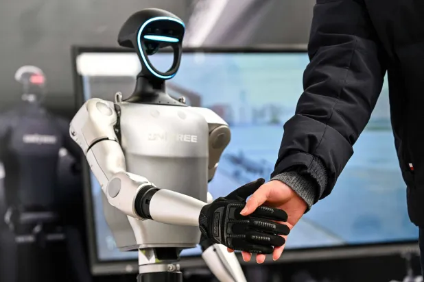 رجل يصافح روبوتاً خلال مؤتمر المطورين العالميين الذي نظمته جمعية صناعة الذكاء الاصطناعي في شنغهاي (أ.ف.ب)