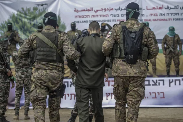 مقاتلان من «كتائب القسام» يرافقان أسيراً إسرائيلياً قبل تسليمه لـ«الصليب الأحمر» في مخيم النصيرات للاجئين وسط قطاع غزة السبت (إ.ب.أ)