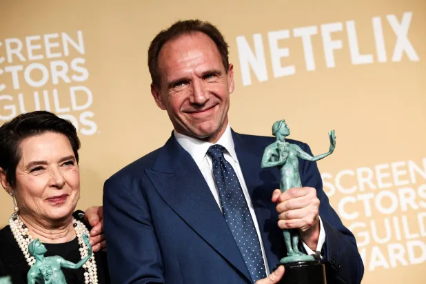 الممثل رالف فاينز يلتقط صورة مع جائزة أفضل أداء لممثل في فيلم سينمائي عن فيلم «كونكلاف» (رويترز)