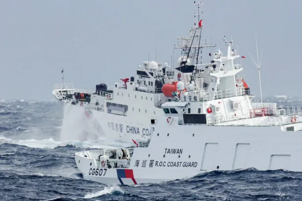 سفينة خفر سواحل تايوانية (يمين) تُراقب سفينة خفر سواحل صينية على بُعد أميال بحرية قليلة من الساحل الشمالي الشرقي لتايوان (أ.ف.ب)