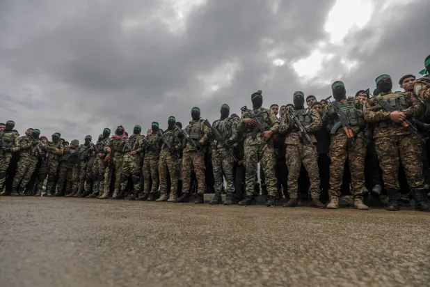 مسلحون من «كتائب القسام» التابعة لحركة «حماس» في أثناء تسليم 3 رهائن إسرائيليين لممثلي الصليب الأحمر في مخيم النصيرات للاجئين وسط قطاع غزة 22 فبراير 2025 (إ.ب.أ)