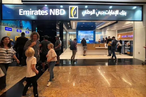 أفراد يدخلون إلى بنك الإمارات دبي الوطني (رويترز)