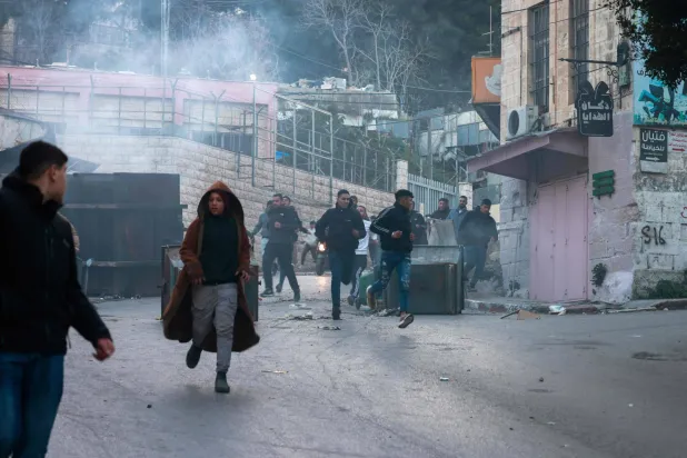 شبان فلسطينيون يتفادون الغاز المسيل للدموع الذي أطلقه الجنود الإسرائيليون خلال مداهمة في نابلس هذا الأسبوع (أ.ف.ب)