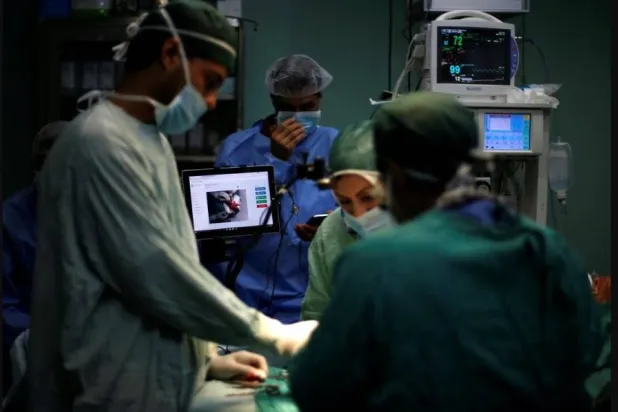 أطباء يتعاونون خلال إجراء عملية جراحية (رويترز)