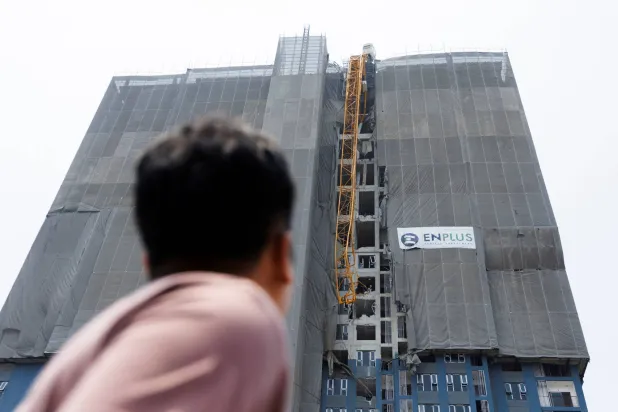 رجل ينظر إلى رافعة متضررة في مبنى قيد الإنشاء بعد زلزال قوي في بانكوك (رويترز)