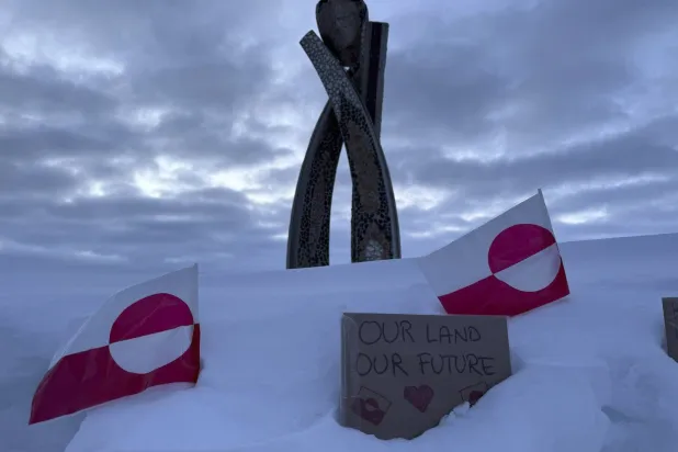 علَمان لغرينلاند يظهران أمام تمثال في نوك (أ.ب)