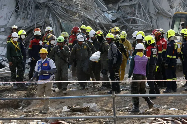 عمال إنقاذ يحملون جثماناً انتشلوه من تحت أنقاض مبنى انهار في بانكوك (إ.ب.أ)