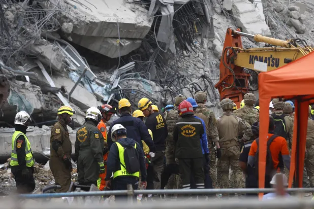 عمال إنقاذ وجنود أميركيون يتفقدون الأنقاض خلال عملية بحث في موقع مبنى انهار إثر زلزال في بانكوك (إ.ب.أ)