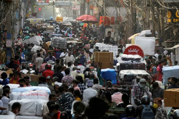 أشخاص يسيرون في سوق مزدحمة بالأحياء القديمة - دلهي بالهند (رويترز)