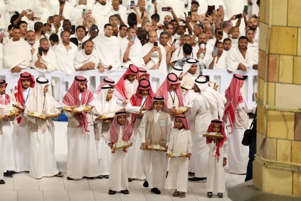 متطوعون يوزعون الحلوى قبل صلاة العيد في الحرم المكي (أ.ف.ب)