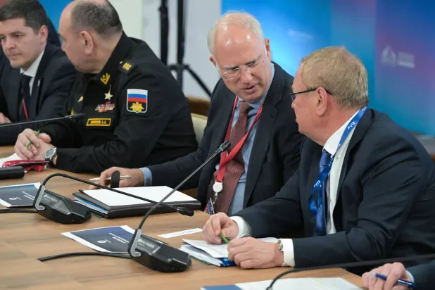 في الوسط الرئيس التنفيذي لصندوق الاستثمار المباشر الروسي كيريل دميترييف خلال اجتماع اقتصادي حضره بوتين في 27 مارس 2025 (إ.ب.أ)