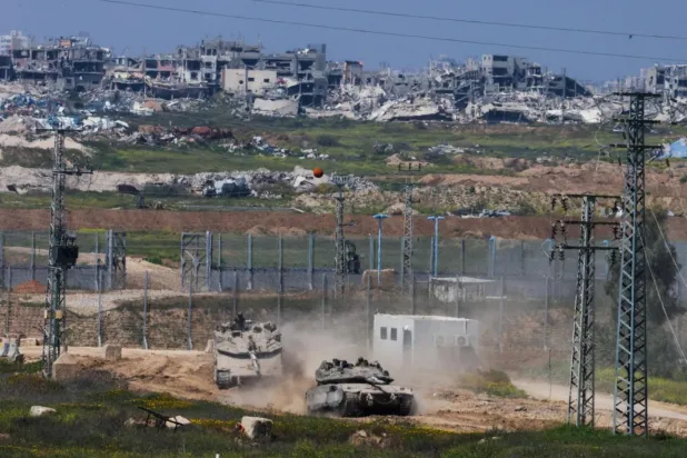 İsrail tankları Gazze sınırında ilerlerken arka planda Gazze Şeridi'ndeki tüm mahalleler görülüyor (AFP)