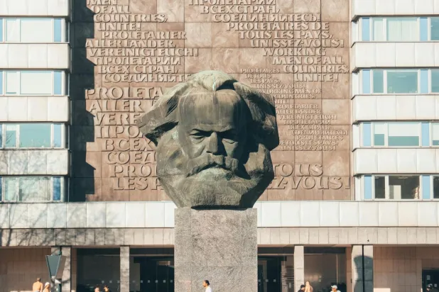 Almanya'nın Chemnitz kentindeki 13 metrelik Karl Marx Anıtı; arkadaki duvarda Komünist Manifesto'daki "Bütün ülkelerin işçileri, birleşin!" cümlesi Almanca, İngilizce, Fransızca ve Rusça olmak üzere 4 dilde yazılı (Unsplash)