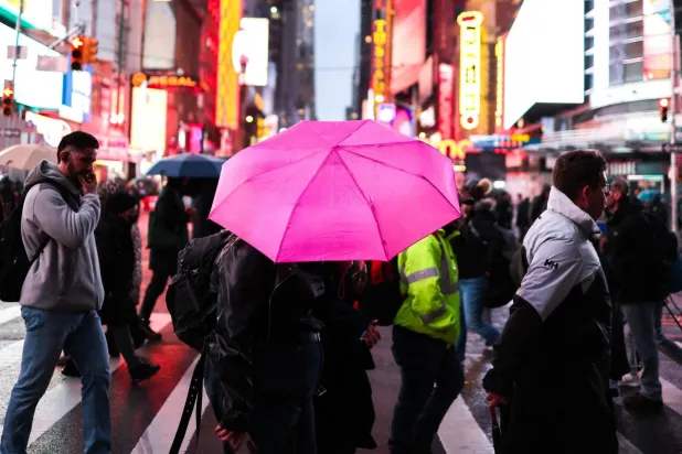 Bir sokaktaki insanlar yağmur altında şemsiyeyle yürüyor (AFP)