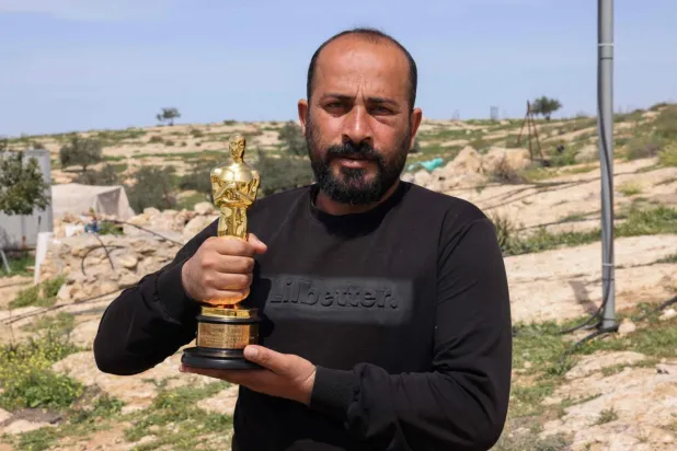 Hamdan Ballal serbest bırakıldıktan sonra yaralı halde Oscar'yla poz verdi (AFP)