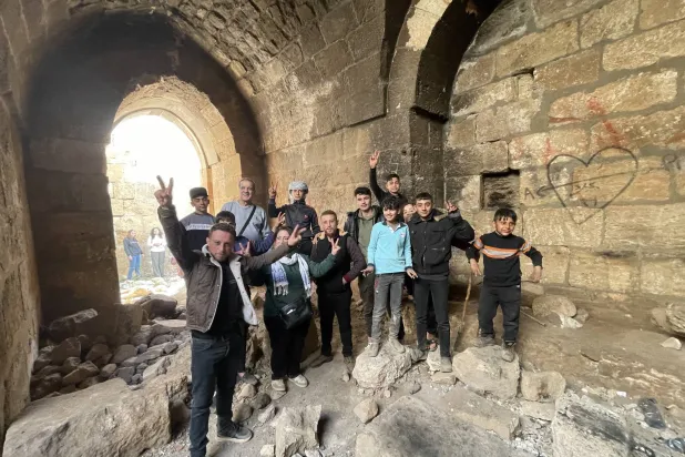 شباب من منطقة حارم في القلعة التاريخية وبدا جزء منها مدمراً (الشرق الأوسط)