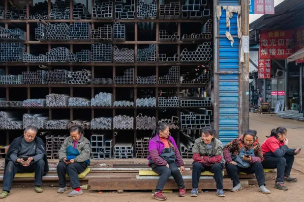 عمال في أحد المتاجر بسوق للصلب في مدينة تشونغقينغ جنوب غربي الصين (أ.ف.ب)