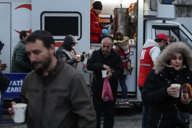 أتراك يحصلون على الحساء الساخن ووجبات إفطار من سيارة للهلال الأحمر في ميدان السلطان أحمد في إسطنبول (إ.ب.أ)