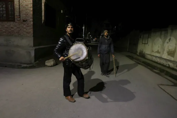 مسحراتي يسير في الشارع وهو يقرع الطبل ويدعو للاستيقاظ (إ.ب.أ)
