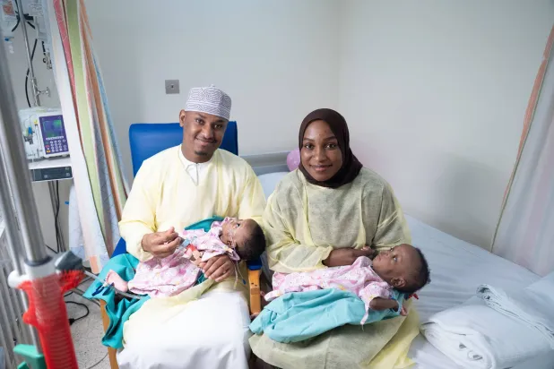 التوأم السيامي بين أحضان والديهما بعد نجاح عملية الفصل (العمانية)