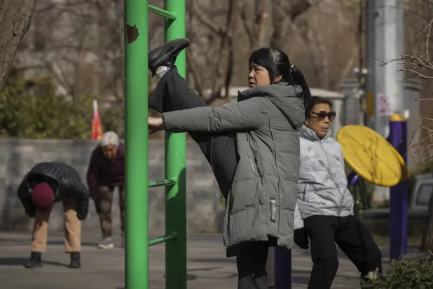 امرأة تمارس تمارين رياضية بالهواء الطلق في بكين (أ.ب)