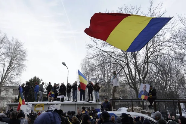 مواطنون يلوحون بالأعلام الرومانية في بوخارست (إ.ب.أ)