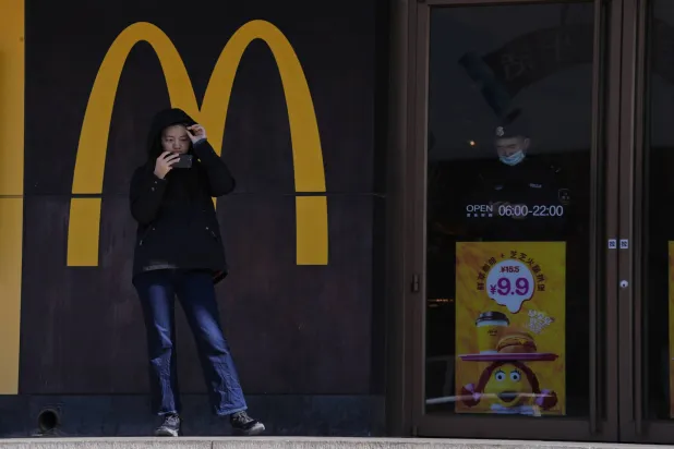 سيدة تمر أمام متجر «ماكدونالدز» في أحد شوارع العاصمة الصينية بكين (أ.ب)