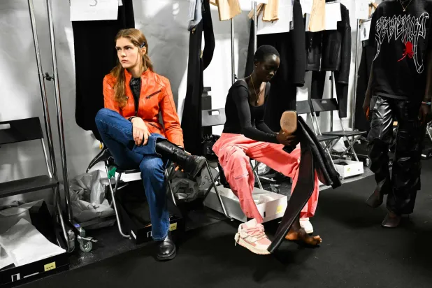 عارضة أزياء ترتدي حذاء في الكواليس قبل بداية أحد العروض بميلان (أ.ف.ب)