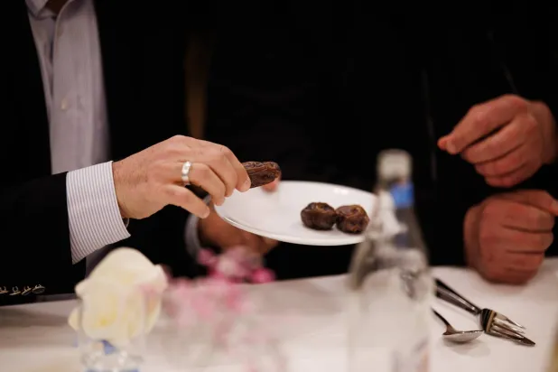 رجل يحمل قطعة من التمر خلال حضوره إفطاراً ضمن شهر رمضان في برلين (إ.ب.أ)