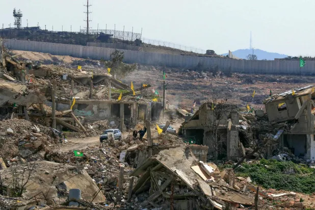 سيارة تمر بجوار المباني المدمرة بسبب الغارات الإسرائيلية في قرية راميا بجنوب لبنان (أ.ف.ب)