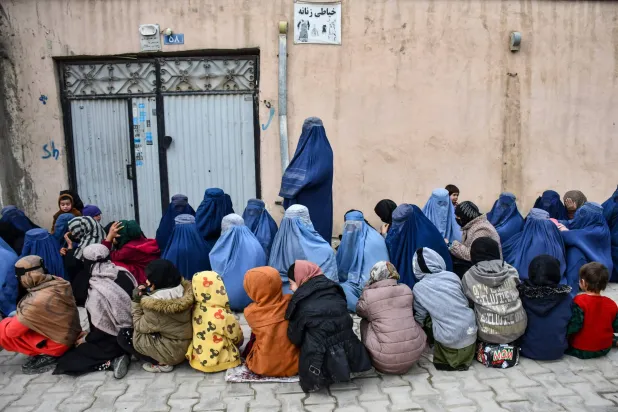 نساء وأطفال أفغان ينتظرون الحصول على مساعدات غذائية من مؤسسة خيرية محلية (أ.ف.ب)