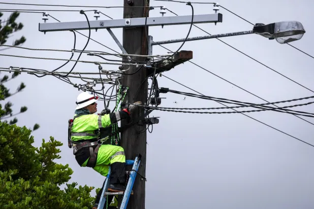 فني يتفقد أسلاك الكهرباء التي تضررت بسبب الإعصار ألفريد (ا.ف.ب)