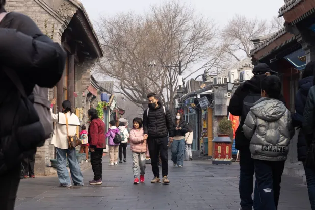 الناس يسيرون في شارع سياحي مزدحم ببكين (إ.ب.أ)