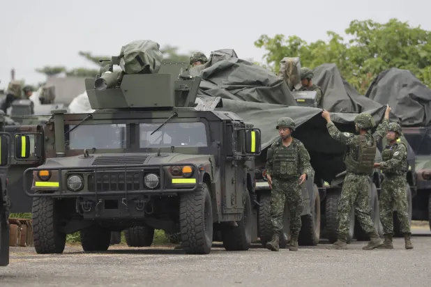 جنود يغطون عربات تحمل منصات صواريخ مضادة للدبابات أثناء تدريبات عسكرية في مقاطعة بينغتونغ جنوب تايوان (أ.ب)