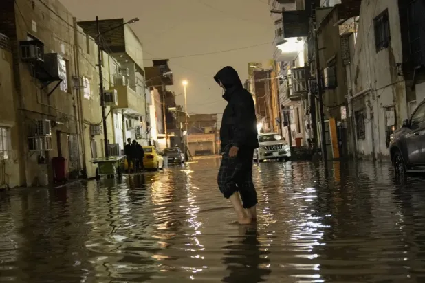 An Iraqi wades through rainwater flooding the streets of Baghdad on March 7, 2025 (AP)
