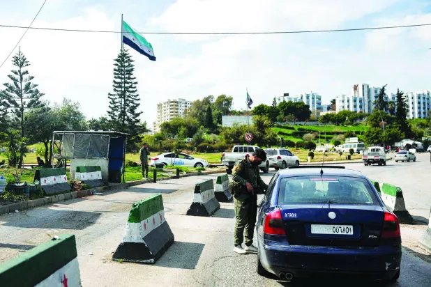 
عنصر أمني يوقف سيارة عند نقطة تفتيش في مدينة اللاذقية الساحلية السورية أمس (أ.ف.ب)