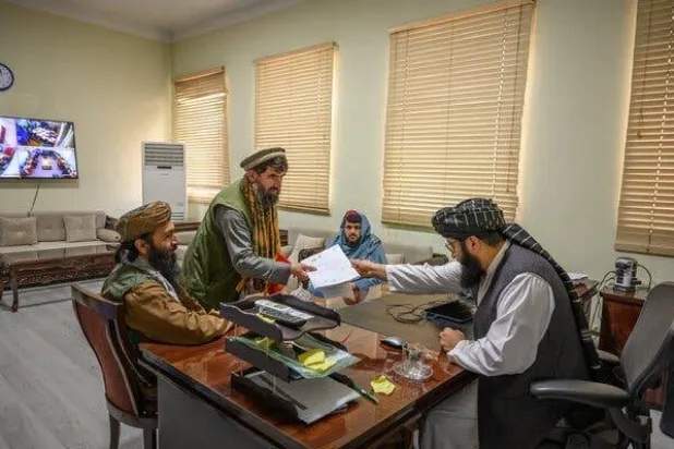 عبد القهار غربندي (على اليمين) مدير مديرية خدمات دافعي الضرائب يسلم وثيقة ضريبية إلى تاجر أحجار كريمة في ديسمبر (نيويورك تايمز)