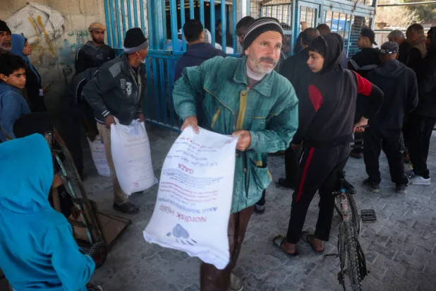 فلسطينيون يصطفون للحصول على مساعدات غذائية من مركز توزيع «الأونروا» في مخيم النصيرات للاجئين وسط قطاع غزة 3 مارس 2025 (أ.ف.ب)