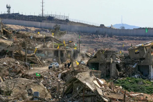 سيارة تمر بجوار المباني المدمرة بسبب الغارات الإسرائيلية في قرية راميا بجنوب لبنان (أ.ف.ب)