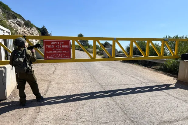 جندي إسرائيلي يقف قرب بوابة على طريق حدودية مع لبنان (رويترز)